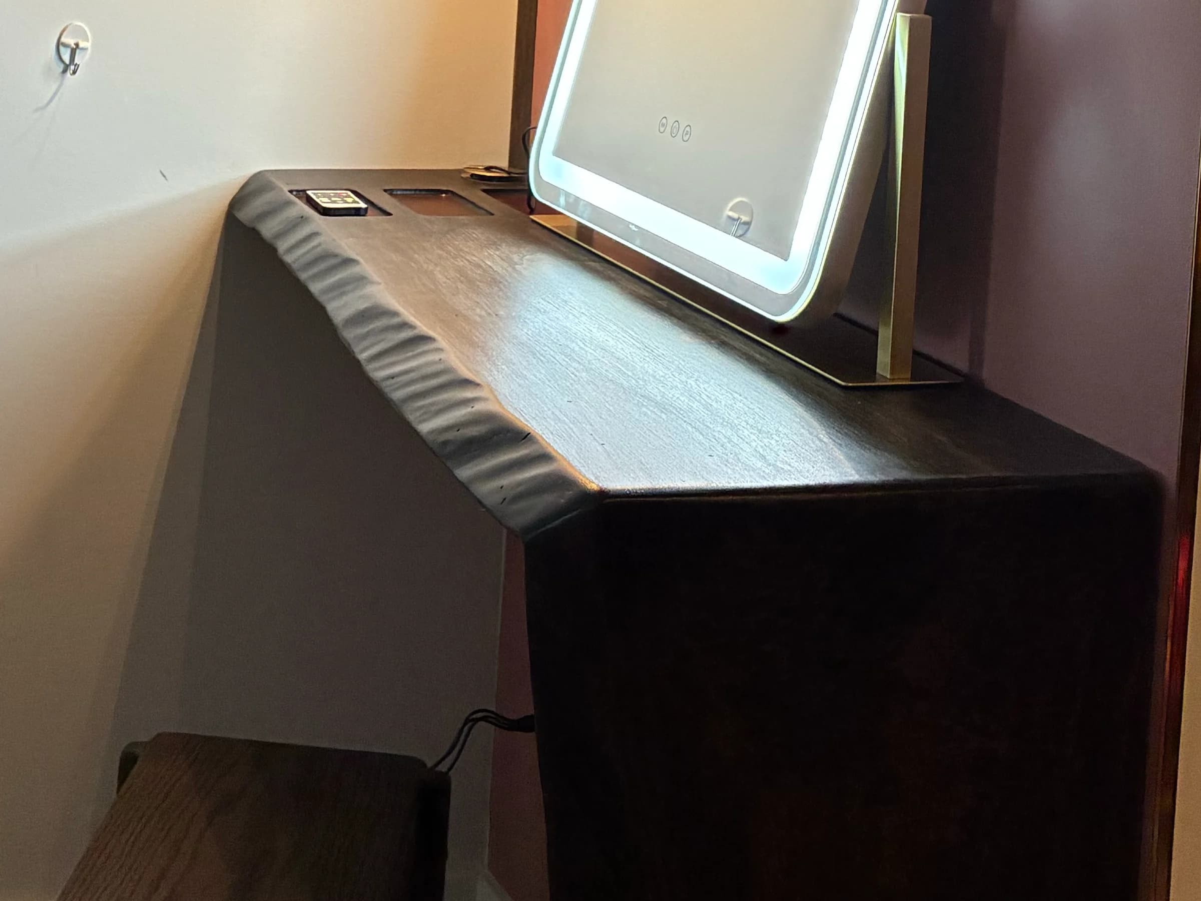 Live edge wood desk fitted into a wall niche beneath a mirror