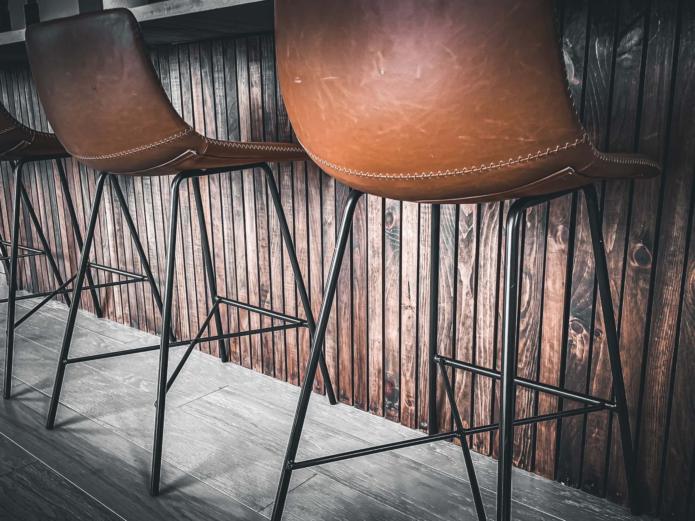 Leather bar stools beside a custom wood-paneled counter