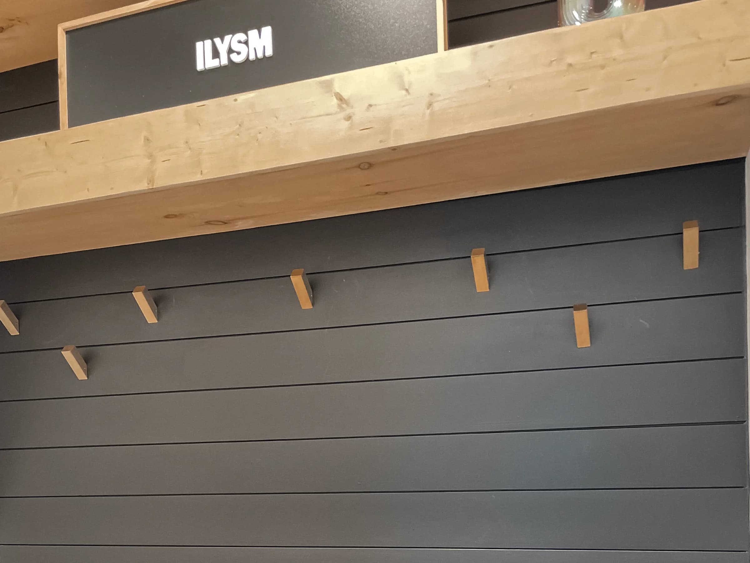 Wood mudroom shelf and hooks against a dark shiplap wall