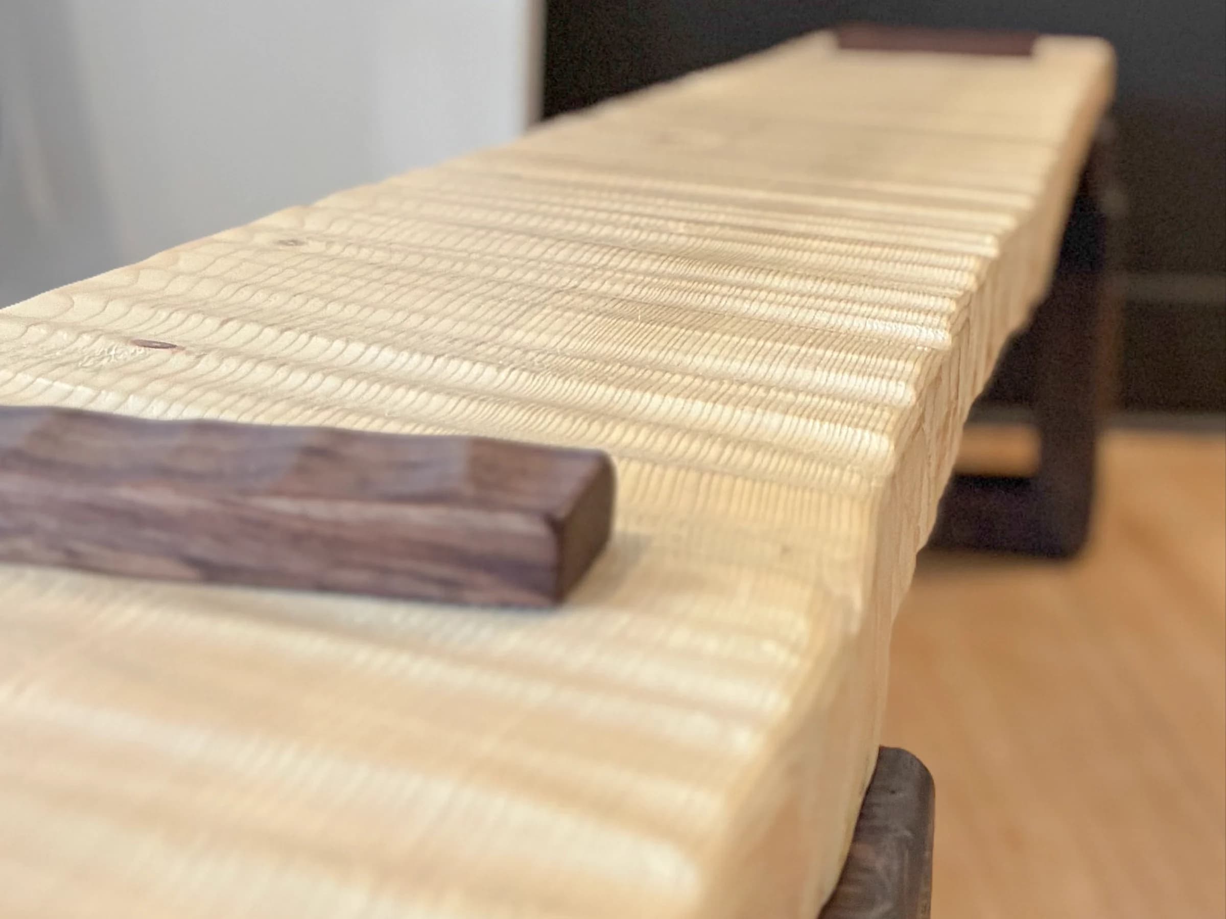 Close-up of a handcrafted wood bench with a textured seat