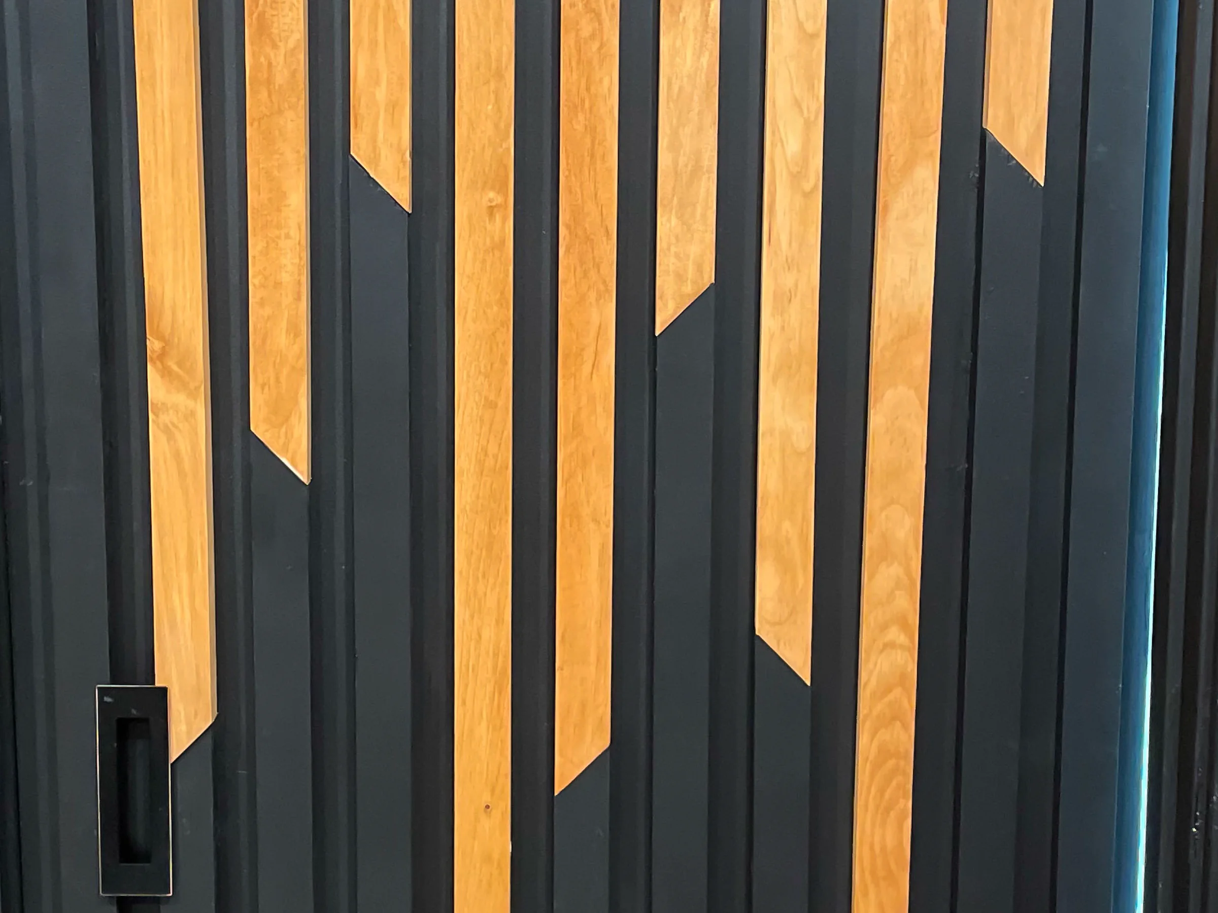 Custom dark wood door with a geometric pattern of contrasting wood slats