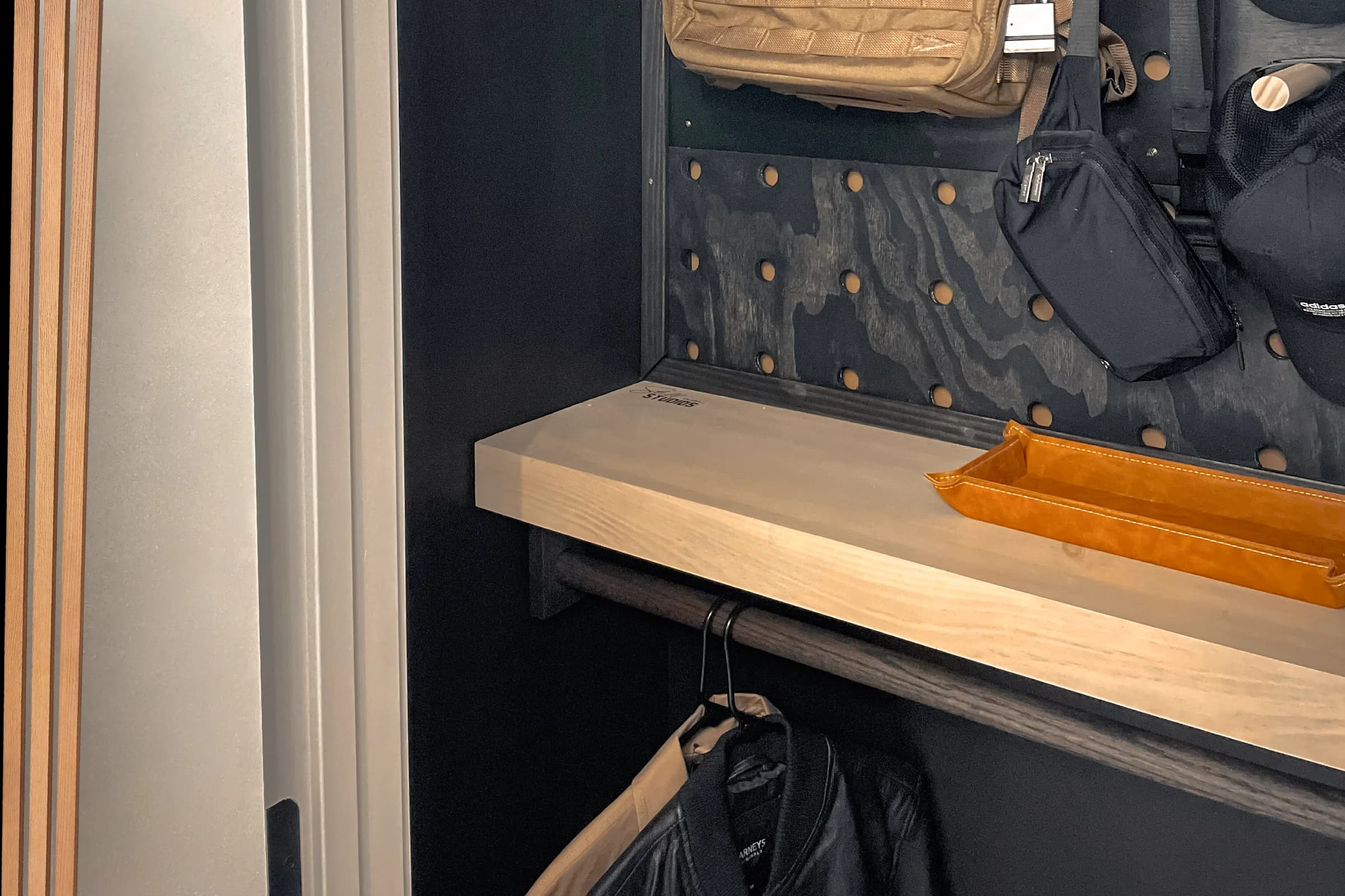 Custom closet worktop with hanging storage and a dark pegboard wall