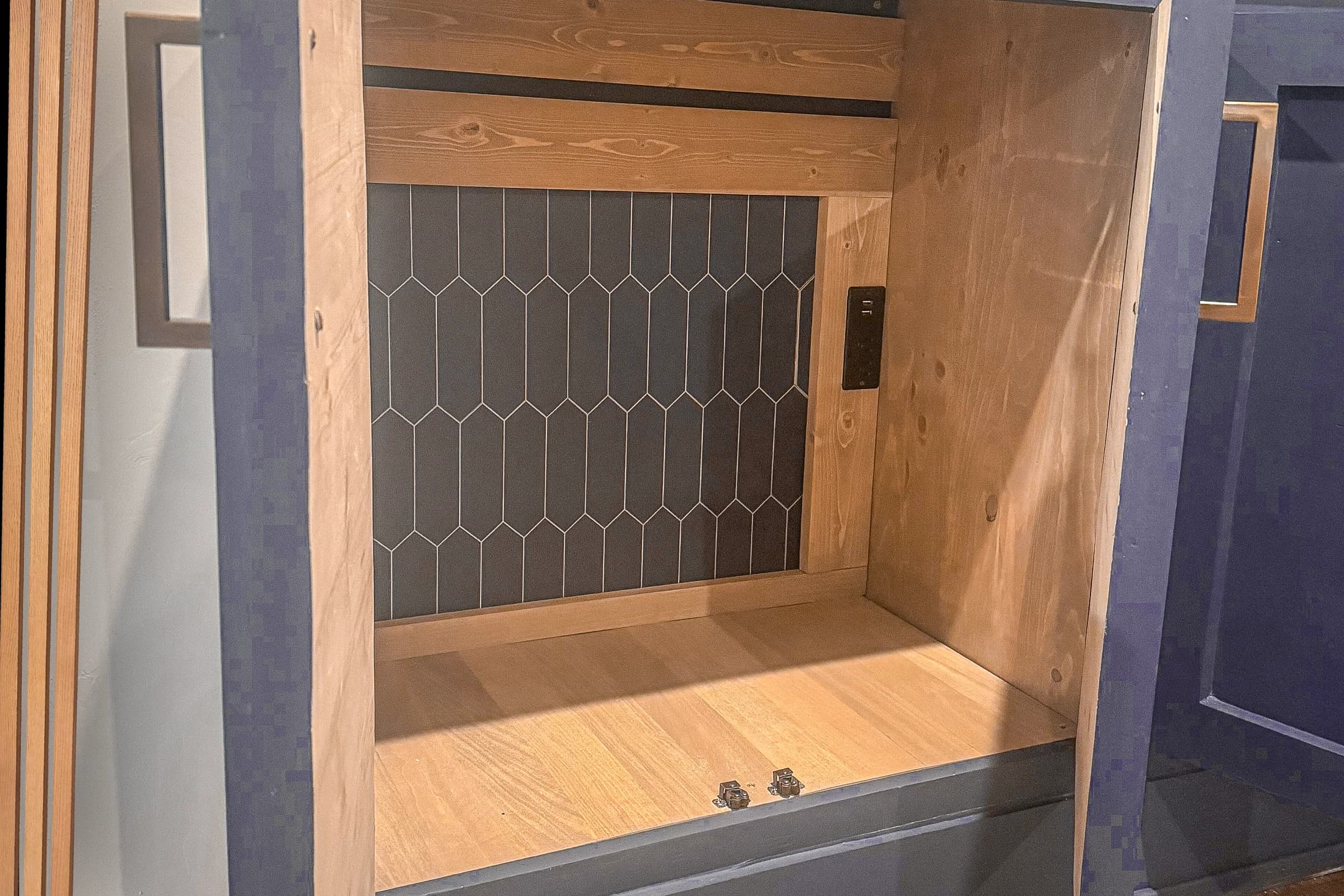 Custom wood-lined built-in cabinet with a counter and patterned tile backing