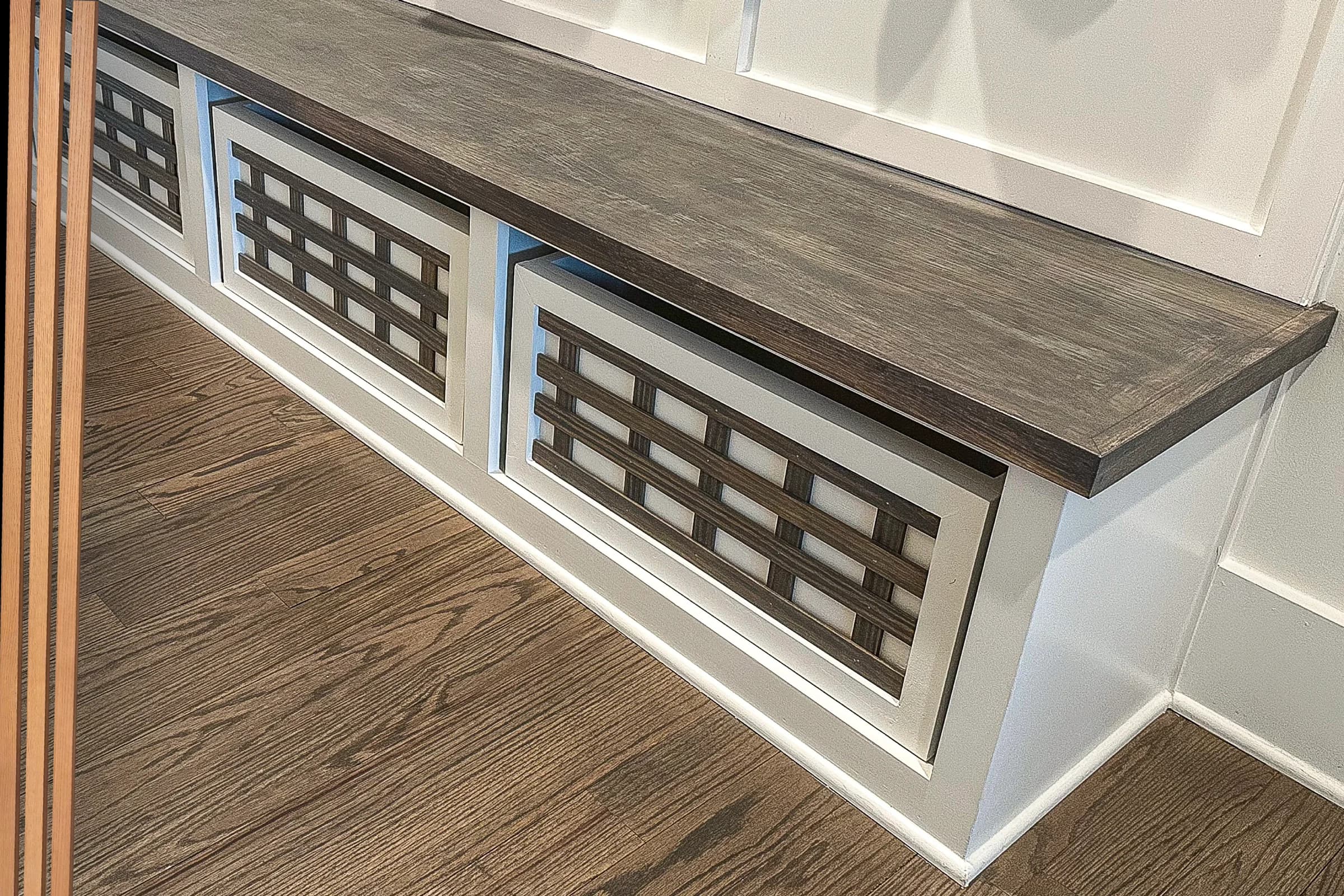 Built-in mudroom bench with a dark wood seat and geometric cabinet panels