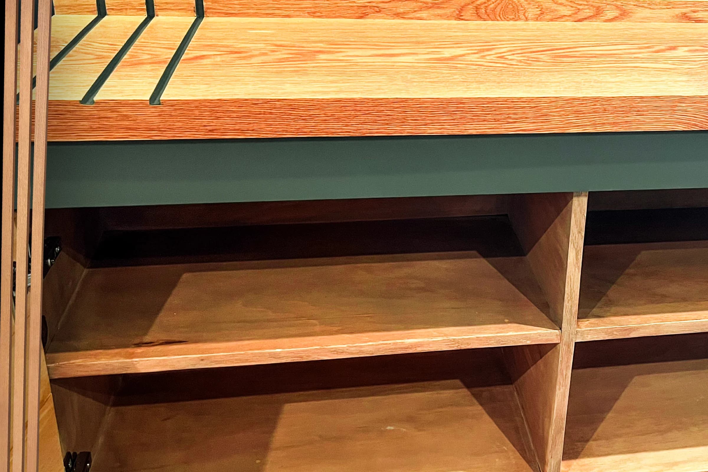 Custom wood mudroom bench with open shoe cubbies and a green frame