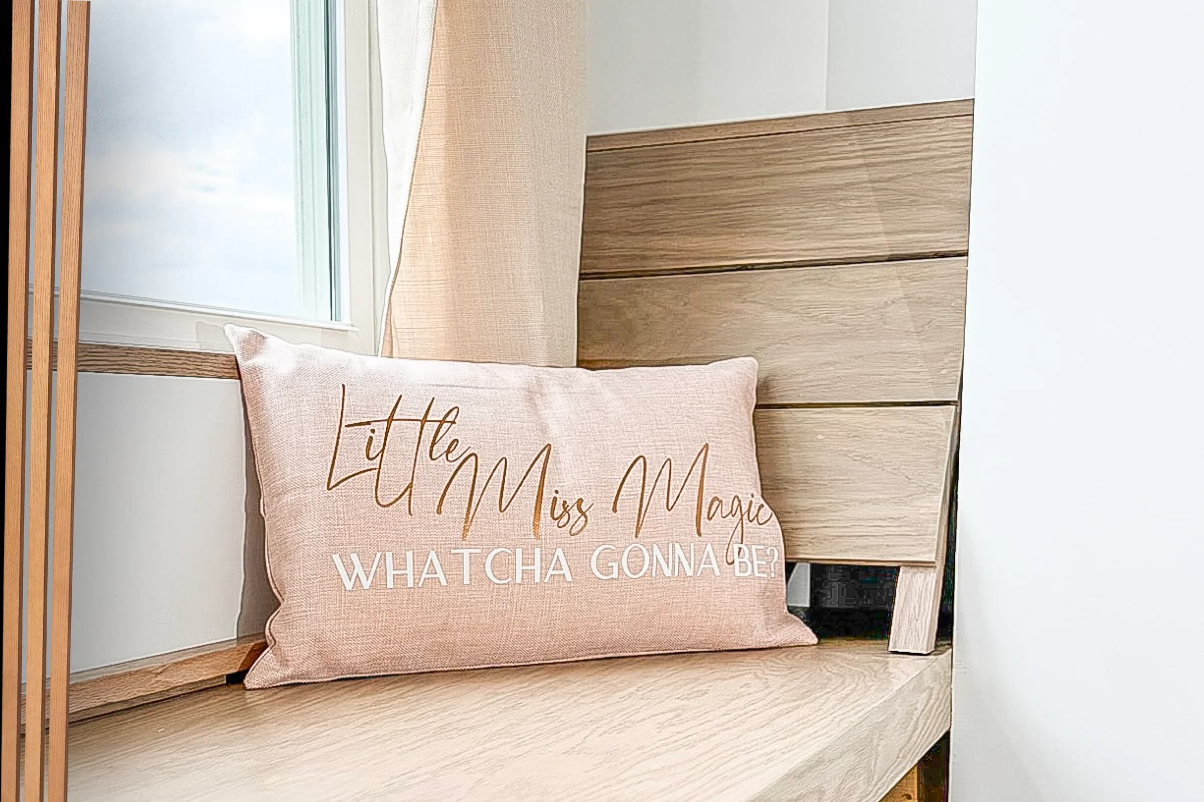 Pale wood reading nook bench beside a window with a decorative cushion