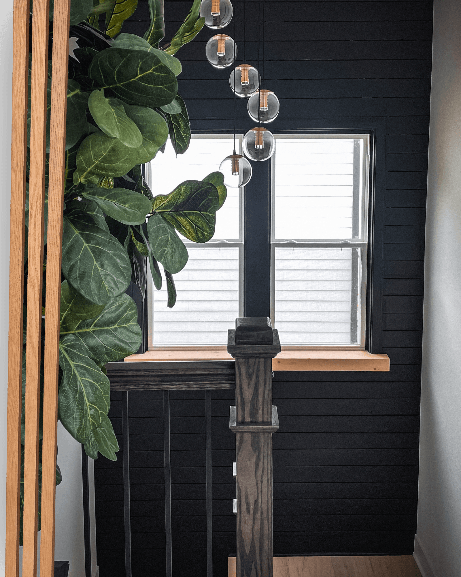 A custom stair landing with dark wood paneling, warm wood trim, and glass pendant lights