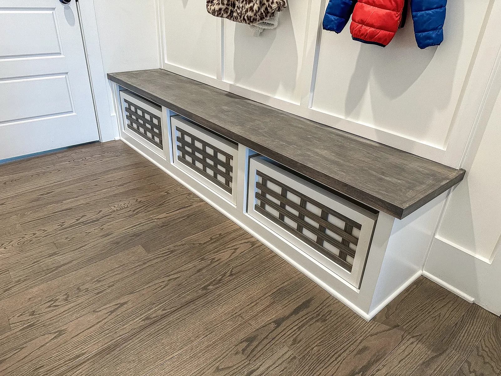 Light wood mudroom bench with cubbies and geometric vent panels